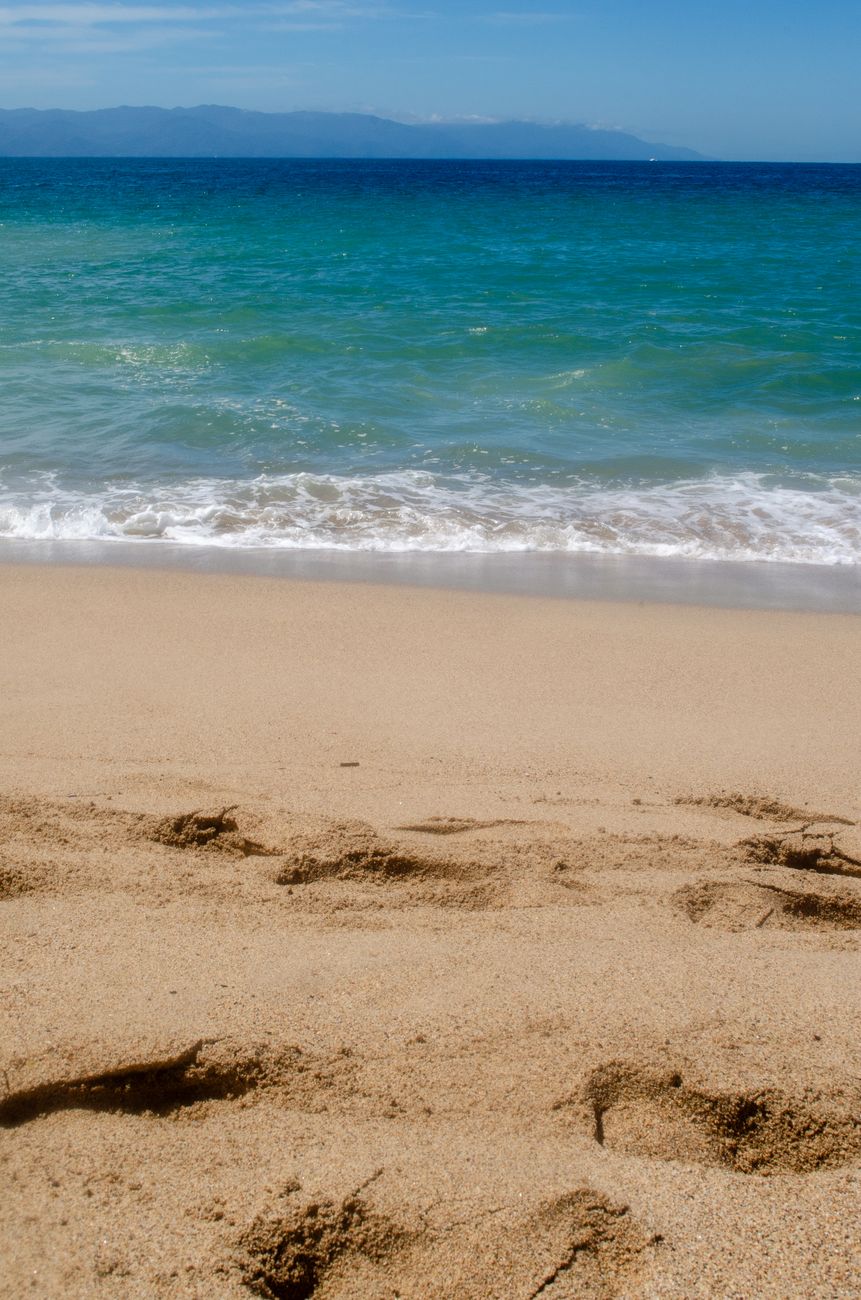 A tranquil coastal scene with clear turquoise waves gently lapping on sandy shores, perfect for relaxation.