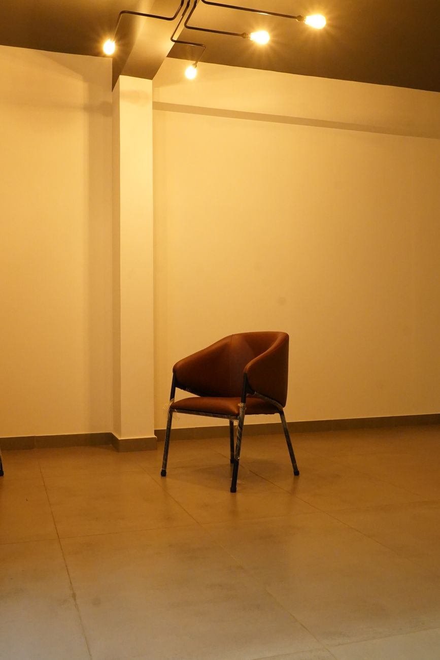 Modern minimalist interior featuring a single brown chair under warm lighting.