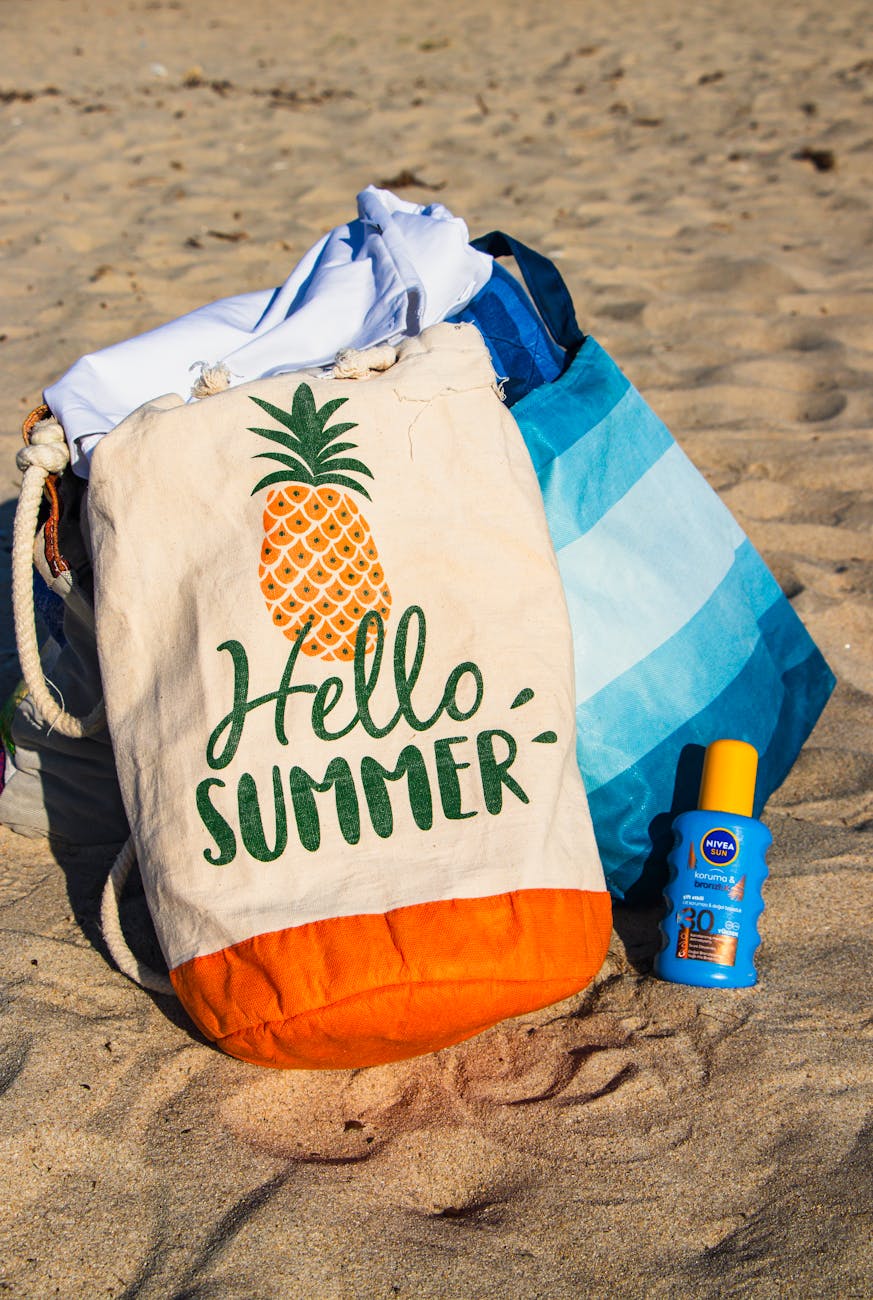 Colorful beach bag and sunscreen evoke a vibrant summer vibe on the sandy beach.