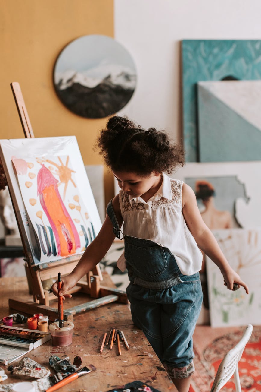 Child artist painting at an indoor studio easel with vibrant creativity.