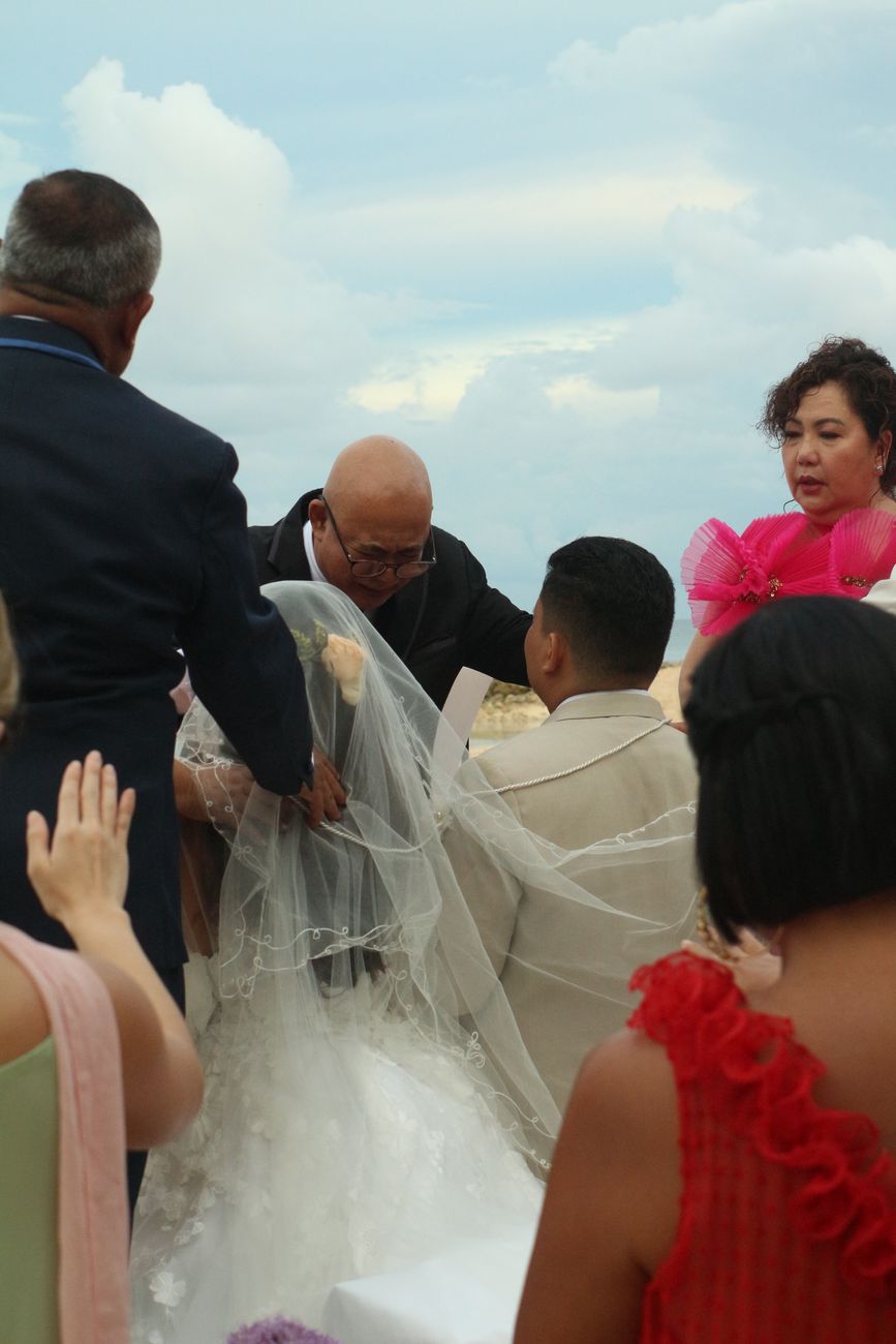 An intimate outdoor wedding ceremony with guests gathered around the bride and groom.