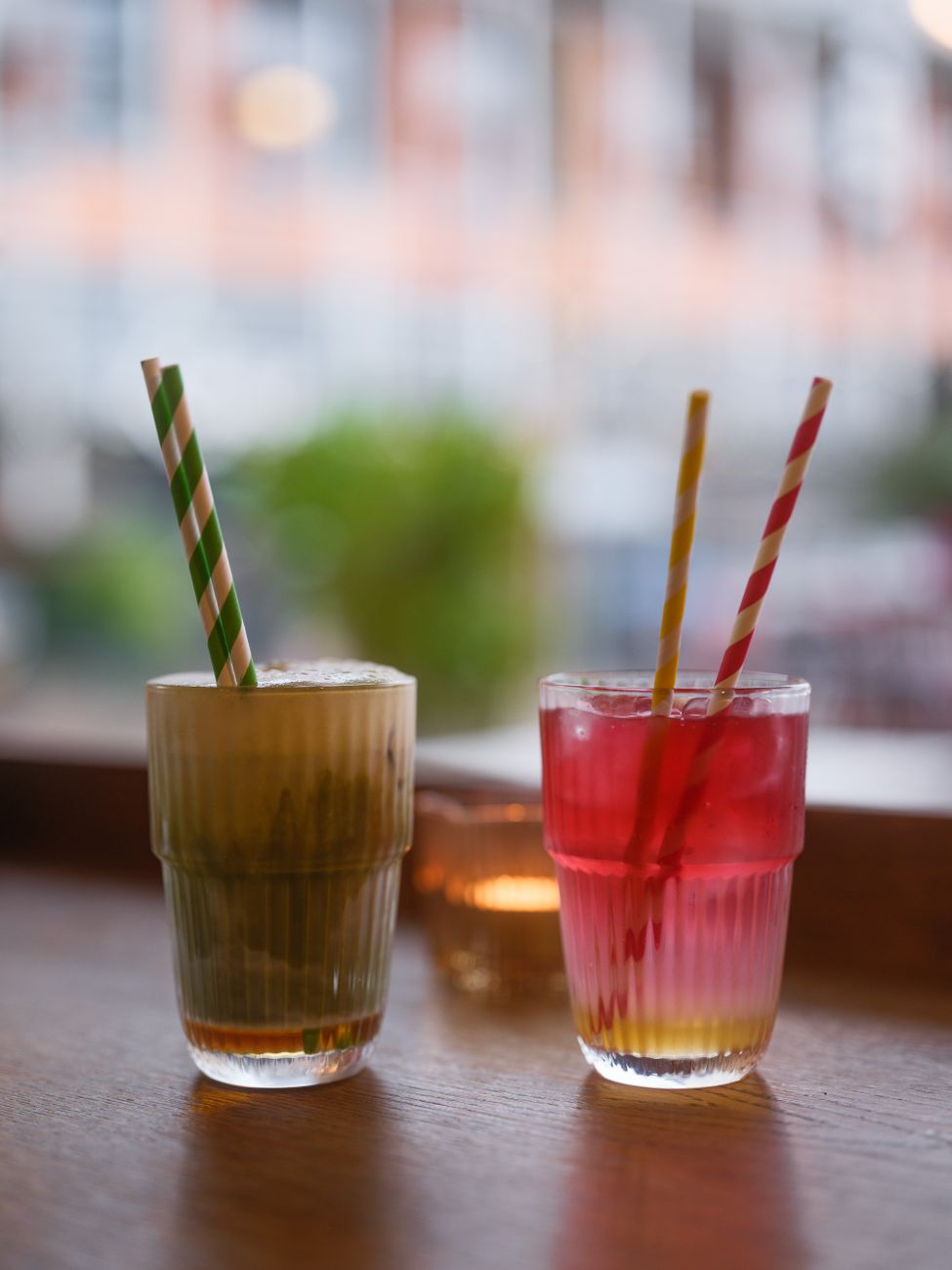 Vibrant drinks with striped straws on a wooden table, creating a cozy indoor ambiance.