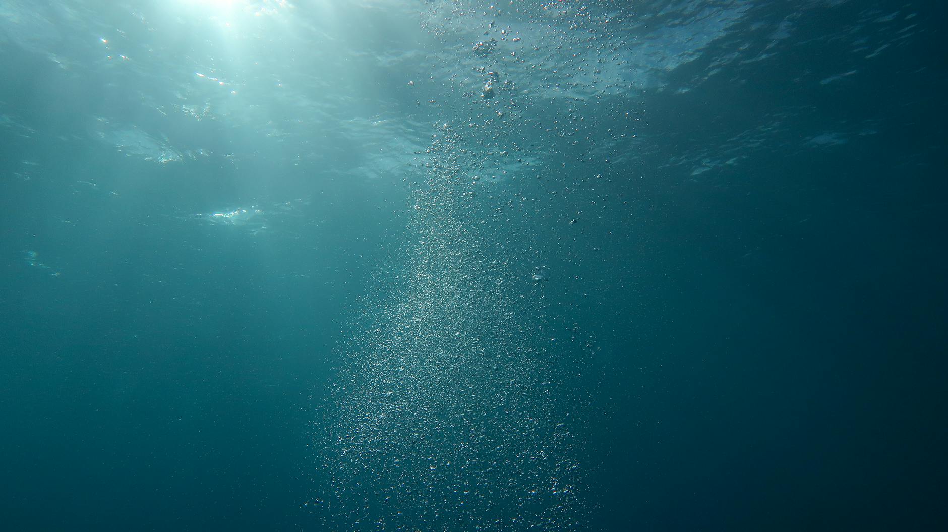 Peaceful underwater scene with sunlight and streaming bubbles in the ocean.