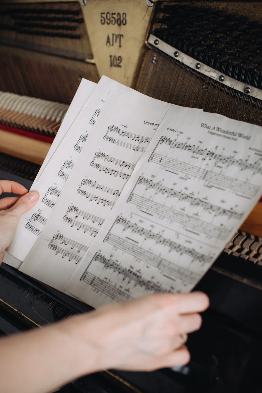 Close-up of a woman's hands turning sheet music at a piano.