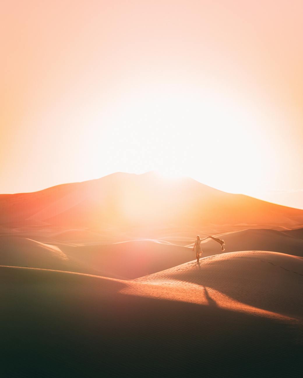 A mesmerizing sunset paints the dunes of Al Wahat Al Dakhla Desert in warm hues, creating a tranquil and scenic landscape.