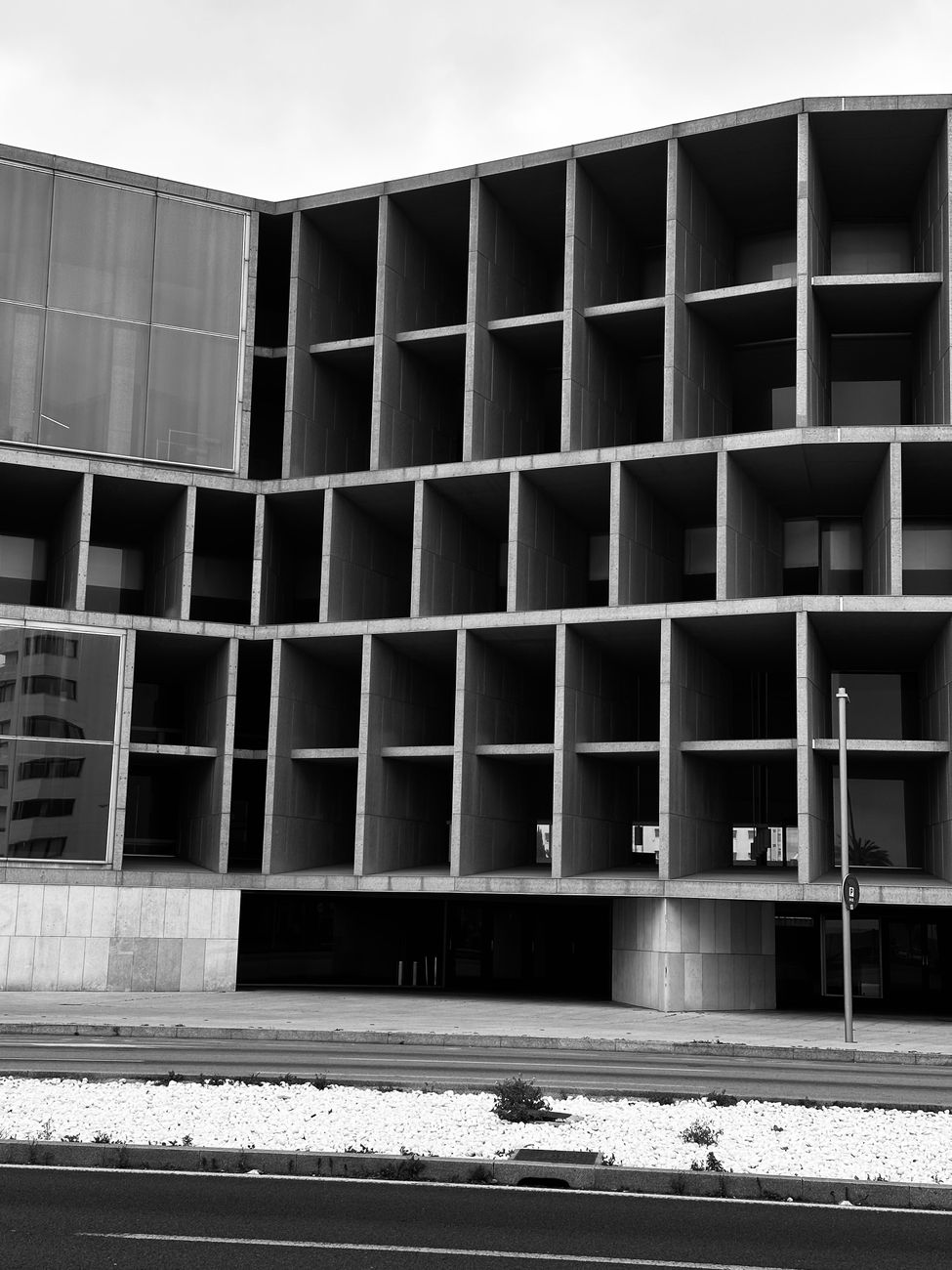 Dramatic black and white photo of modern building facade with repetitive geometric design.