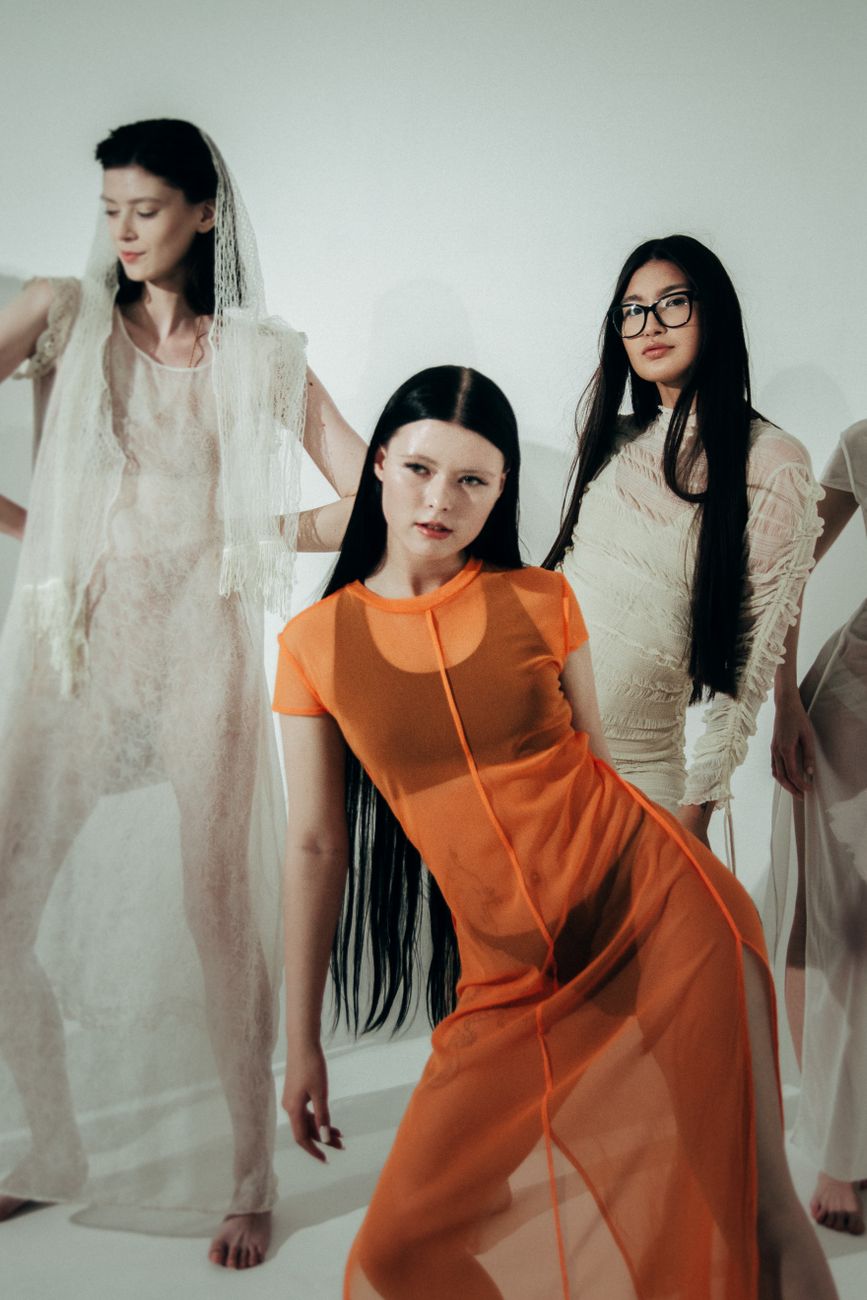 Three models posing in avant-garde dresses on a white background. Stylish and artistic composition.