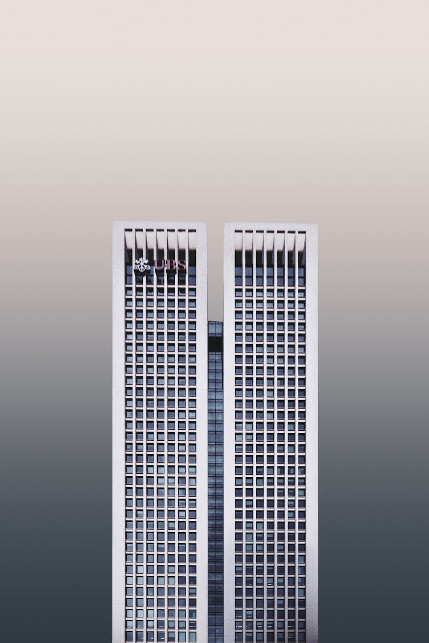 A modern twin skyscraper with a minimalist facade against a neutral sky.