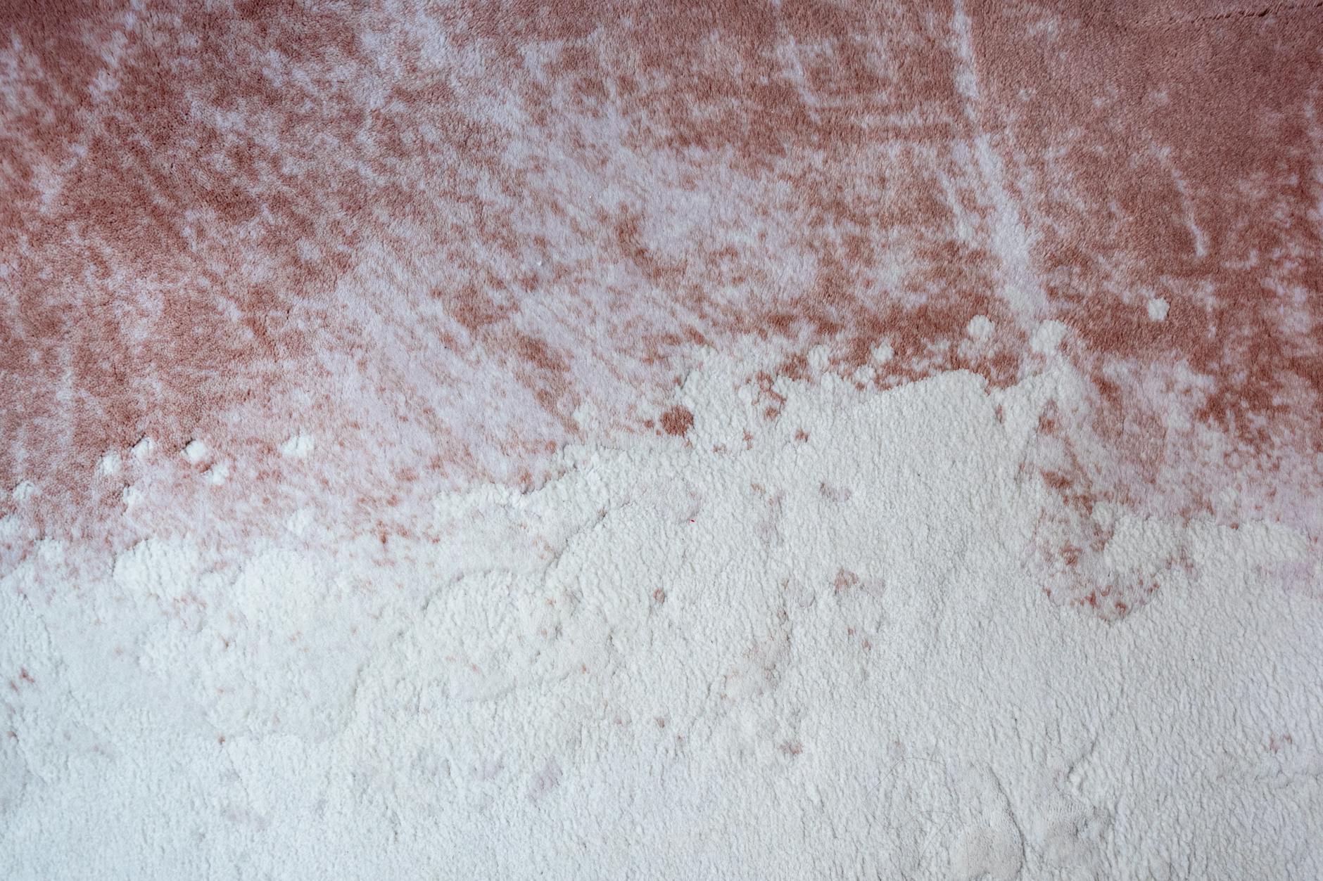 Close-up abstract texture of a pink and white surface resembling plaster or paint.