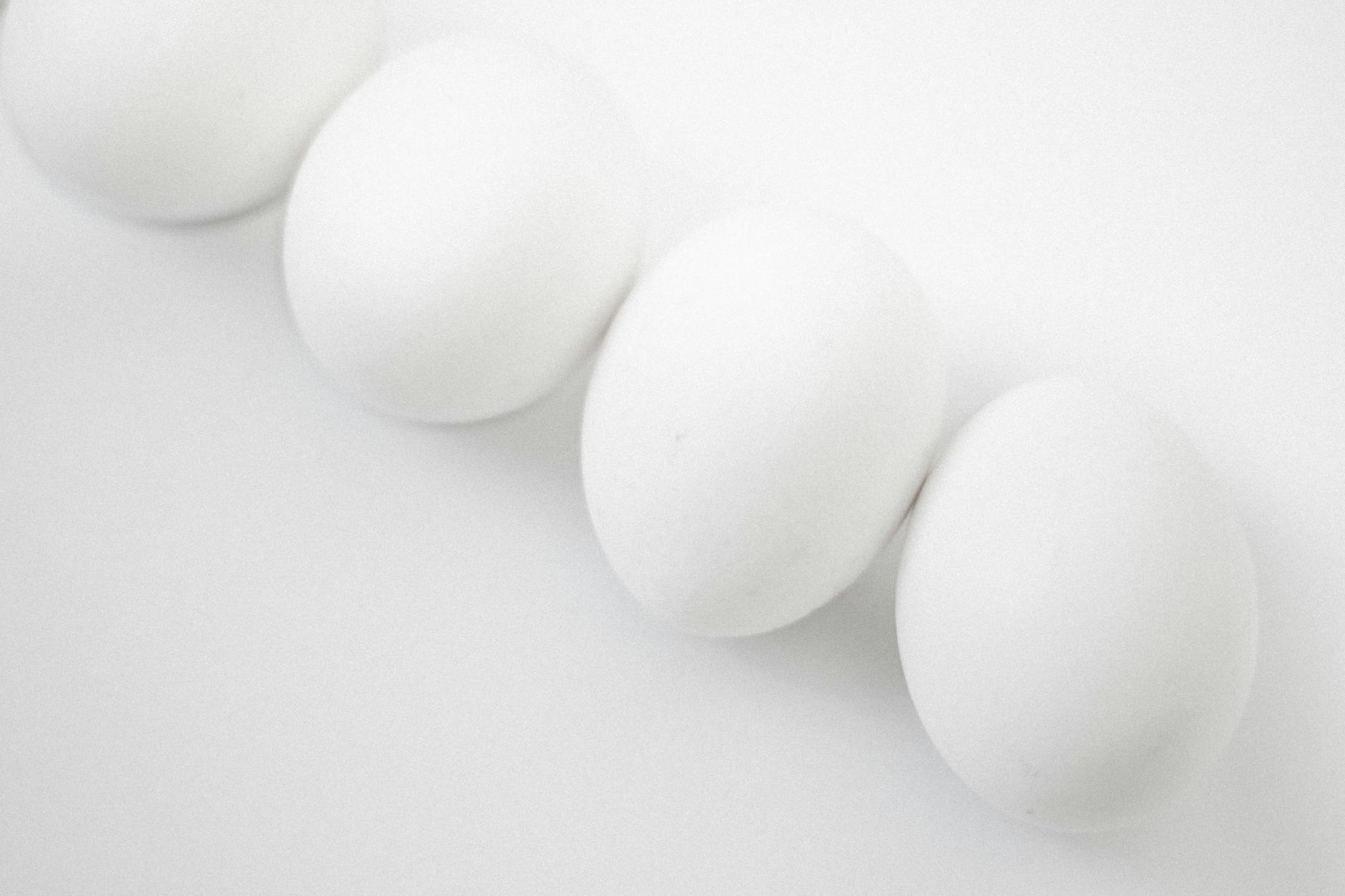 Four clean white eggs on a smooth background, showcasing minimalism.