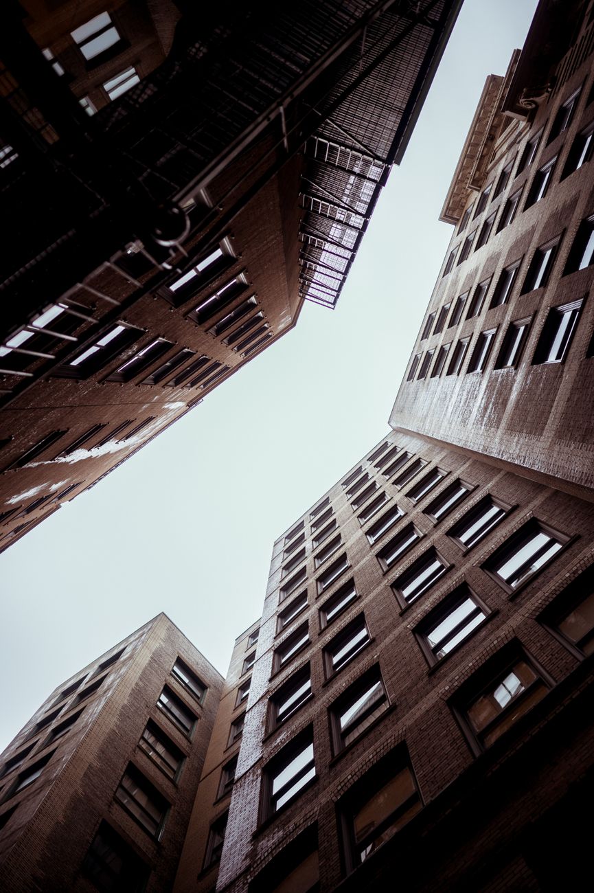 Dramatic low angle shot of tall, red brick residential skyscrapers in an urban courtyard.
