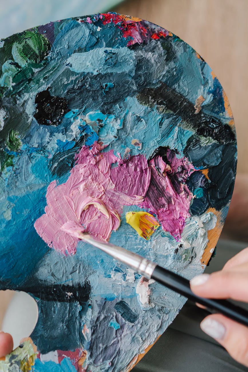 An artist mixes vibrant colors on a palette with a paintbrush, showcasing creativity.