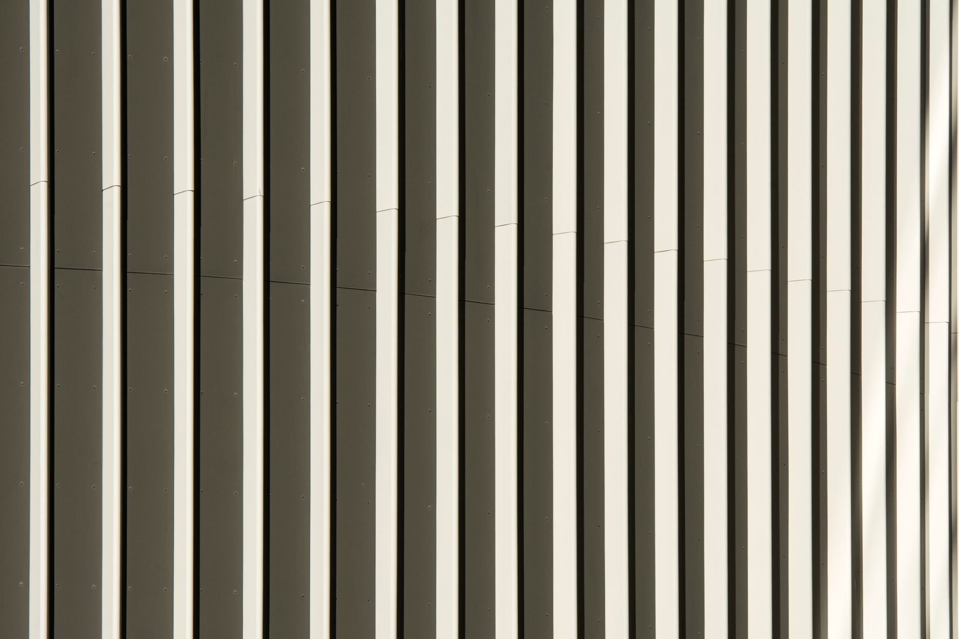 Close-up view of a modern building facade showcasing abstract vertical patterns in neutral tones.
