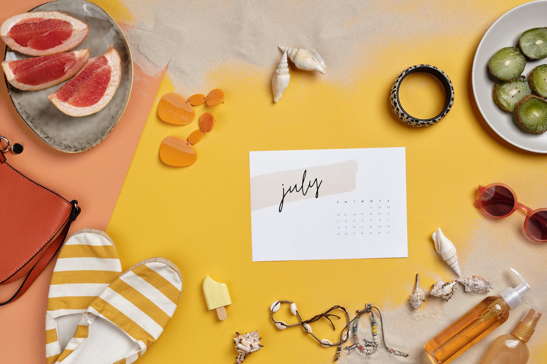 Summer-themed flat lay with vacation essentials like sunglasses, fruits, and calendar on sand.