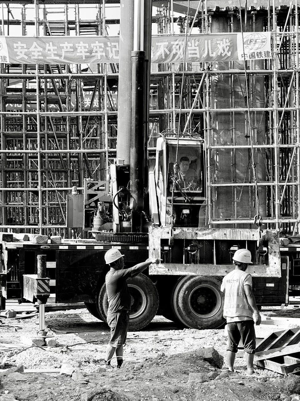 Black and white image showing construction workers and equipment on a busy building site in Shanghai.