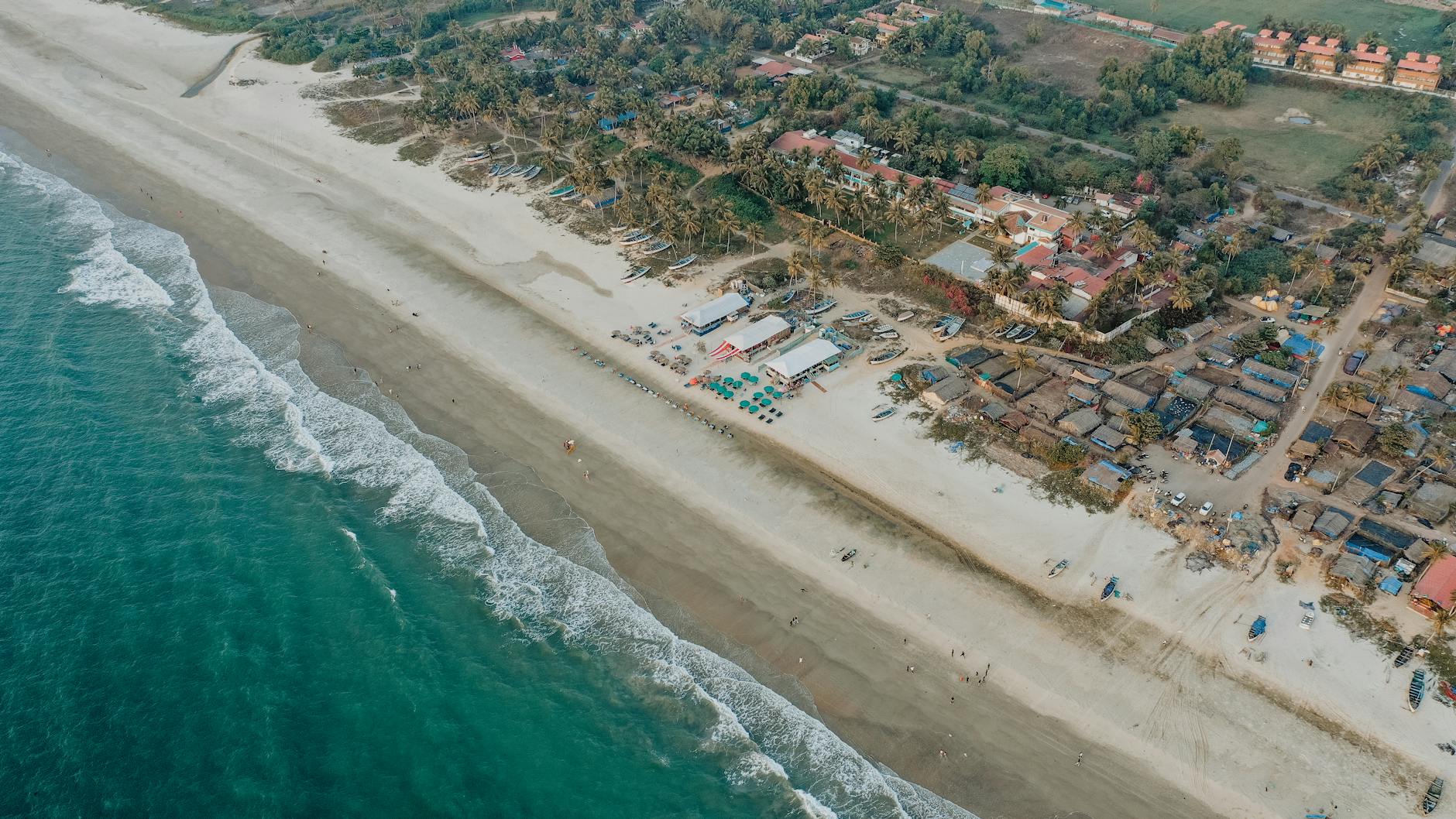 Aerial shot of a picturesque beach and village along the coastline of Goa, India.