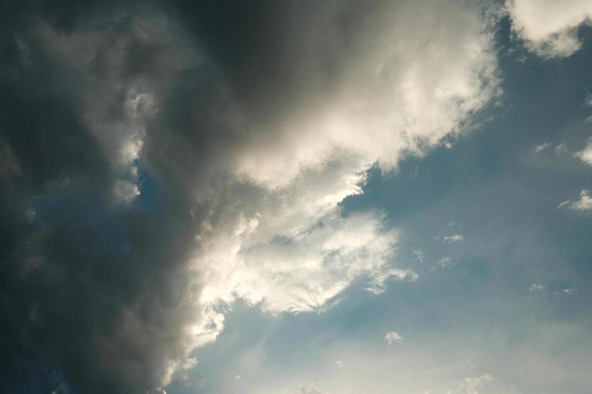 Moody sky with dramatic storm clouds revealing bright sunlight. Ideal for weather and nature themes.