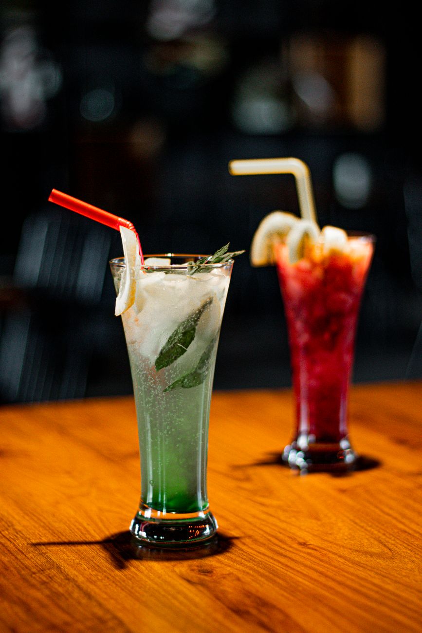 Refreshing colorful cocktails on a wooden table, perfect for a night out in a dimly lit bar.