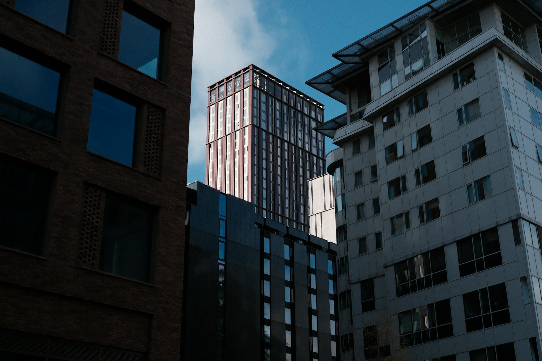 A view of modern skyscrapers framed by contemporary buildings under a clear blue sky.