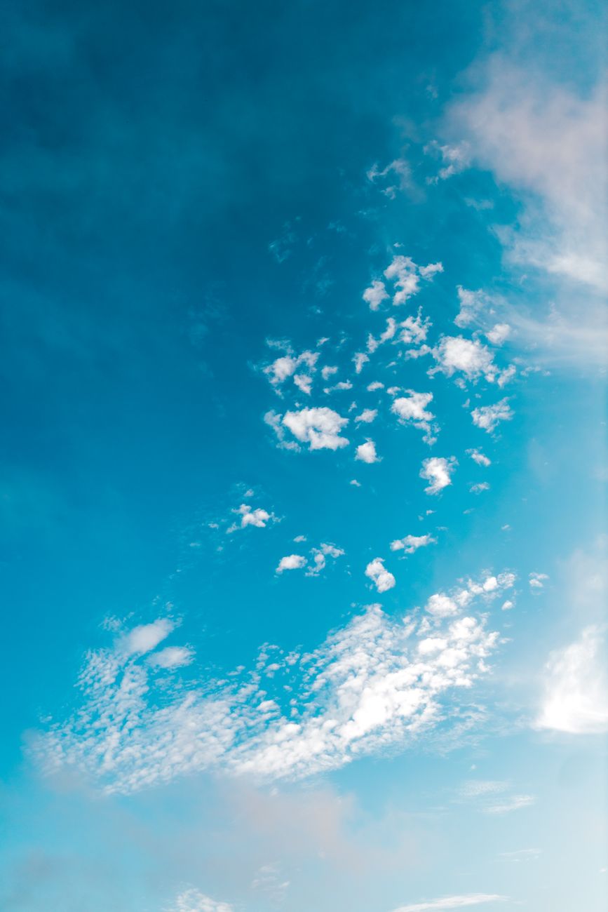 A bright blue sky filled with scattered white clouds captured from a low angle outdoors.