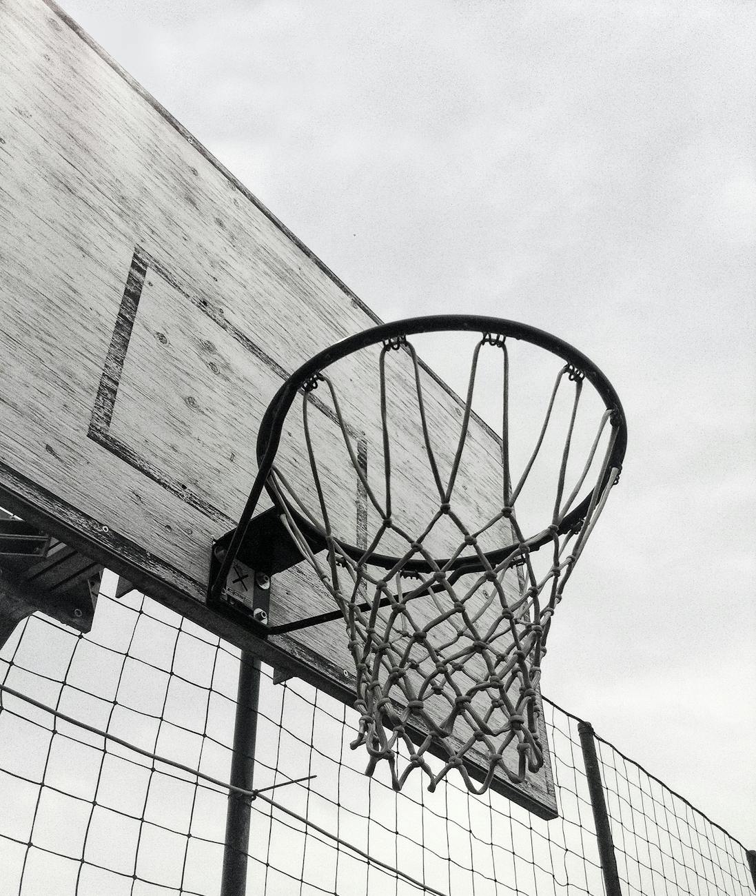 Monochrome shot of a basketball hoop against the sky, capturing the essence of outdoor sports.