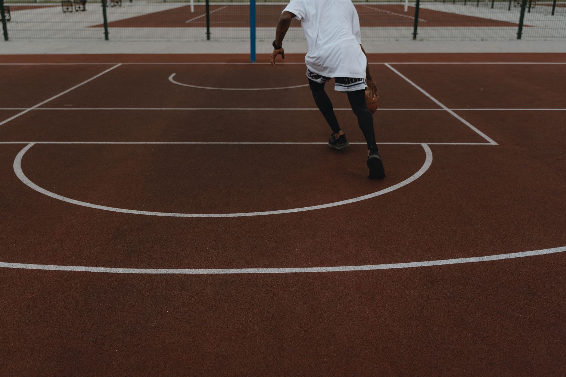 Vibrant outdoor basketball scene with an athlete dynamically dribbling on the court.