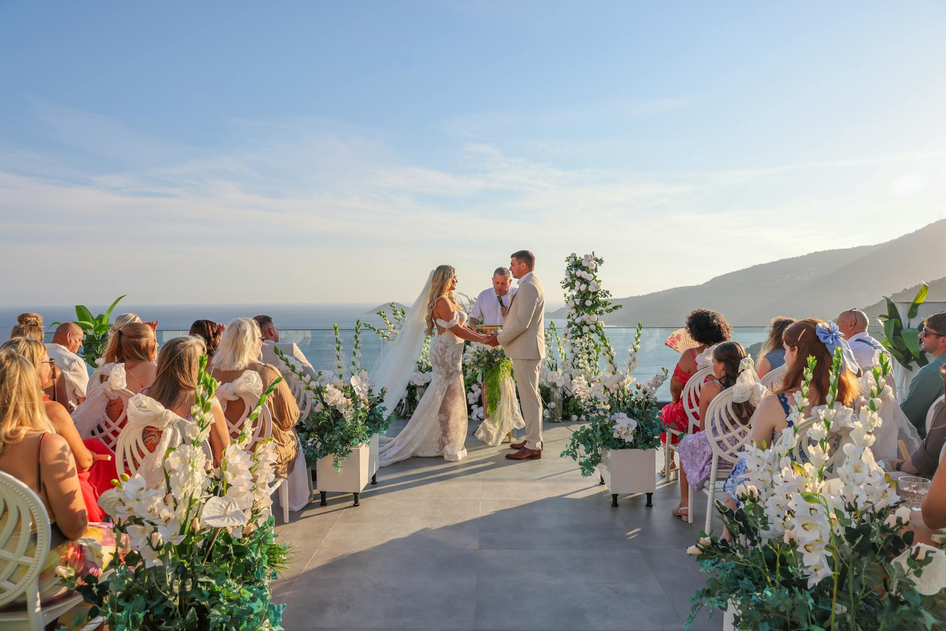 Elegant outdoor wedding ceremony with ocean view and floral decor.