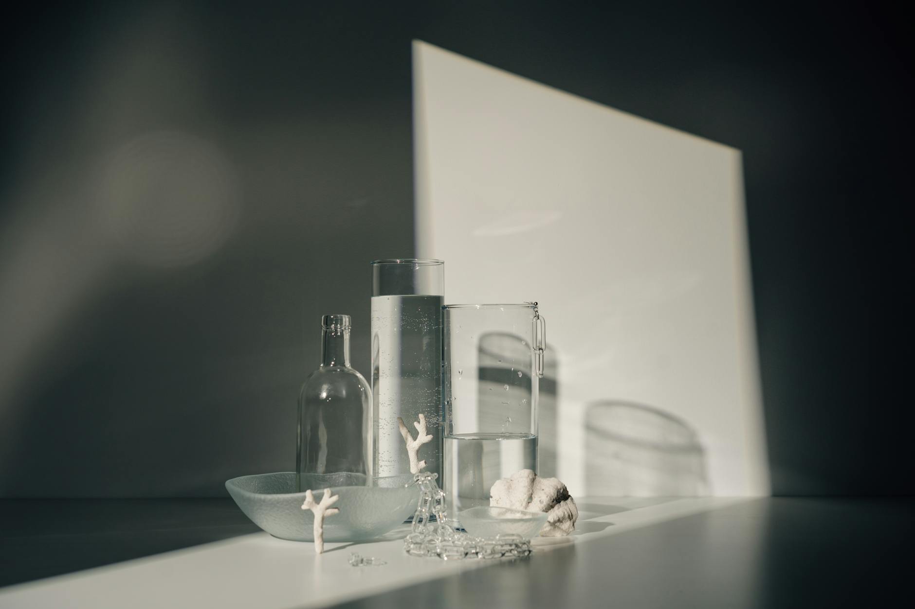Artistic still life of glass bottles and objects casting dramatic shadows.