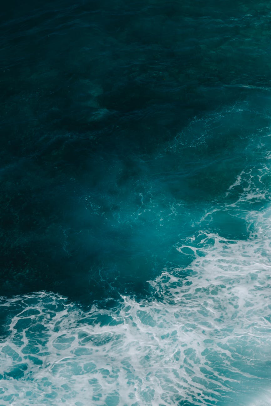 A tranquil view of ocean waves with deep blue hues captured from above, conveying serenity.