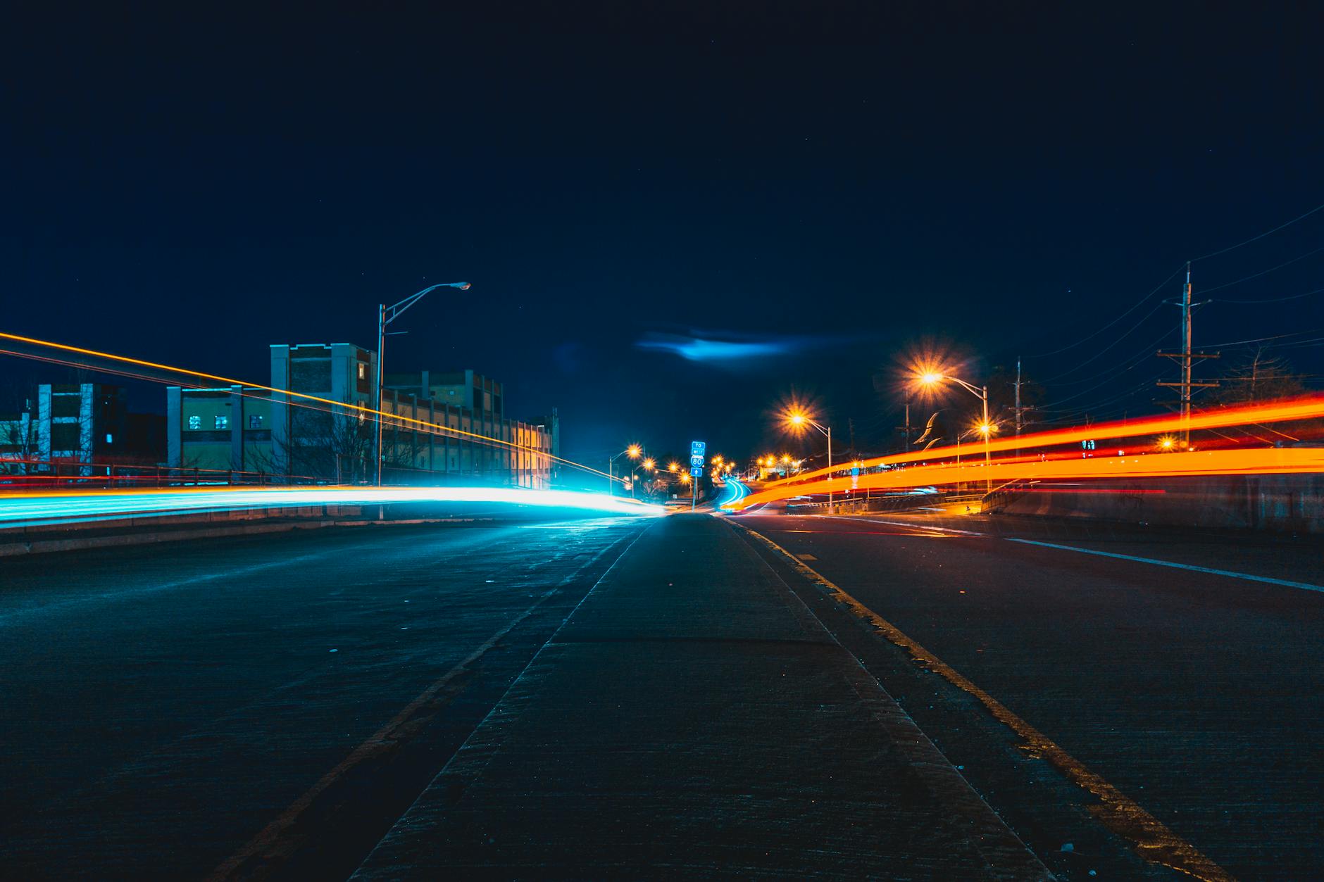 Captivating night cityscape with vibrant light trails on an urban highway, showcasing dynamic movement and city lights.