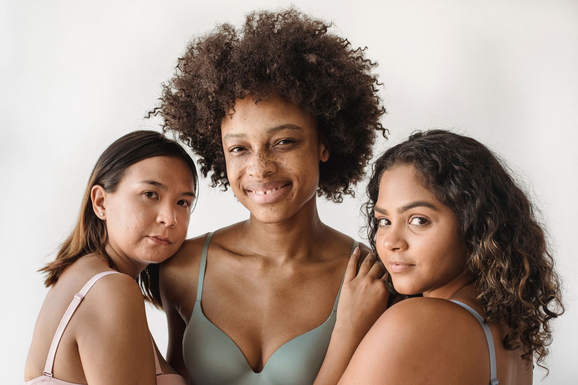 Three diverse women confidently posing together in stylish underwear against a white background.