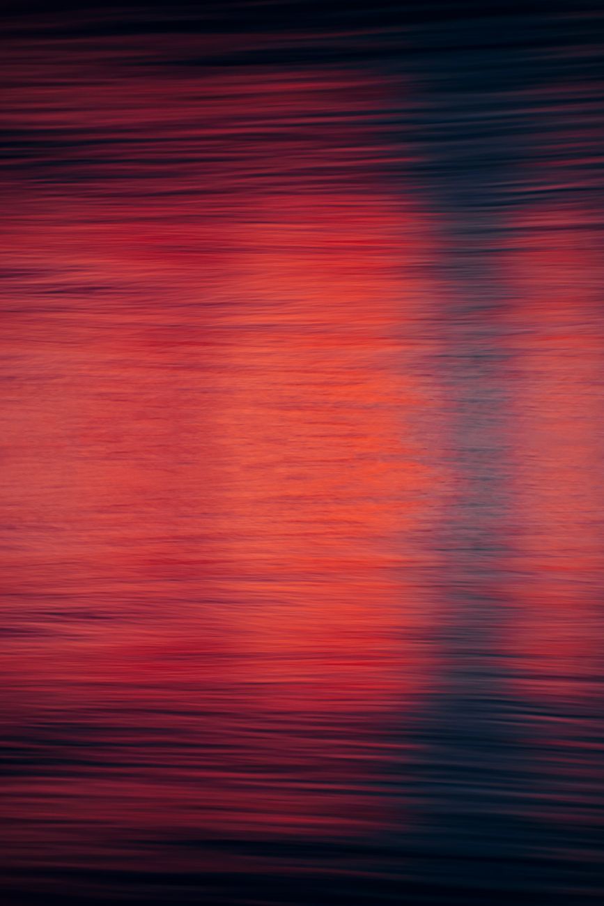 Abstract image featuring blurred red and blue colors resembling water reflections, creating a dynamic and artistic look.