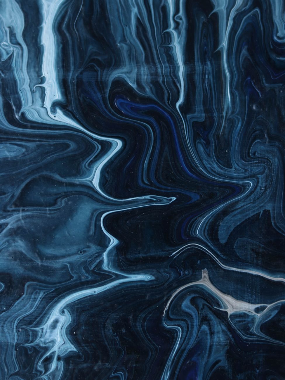Fluid art with swirling blue and black tones creating a dynamic abstract pattern.