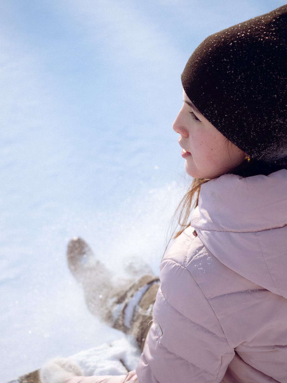 Side view of a woman in winter attire enjoying a snowy landscape, showcasing stylish fashion.