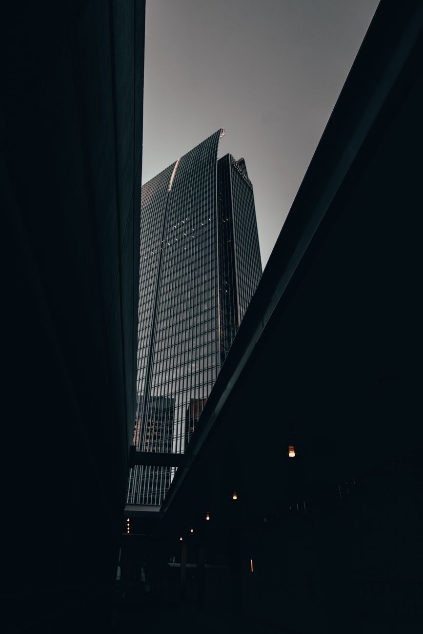 A low angle view of a modern skyscraper with a sleek steel and glass facade, photographed at dusk.