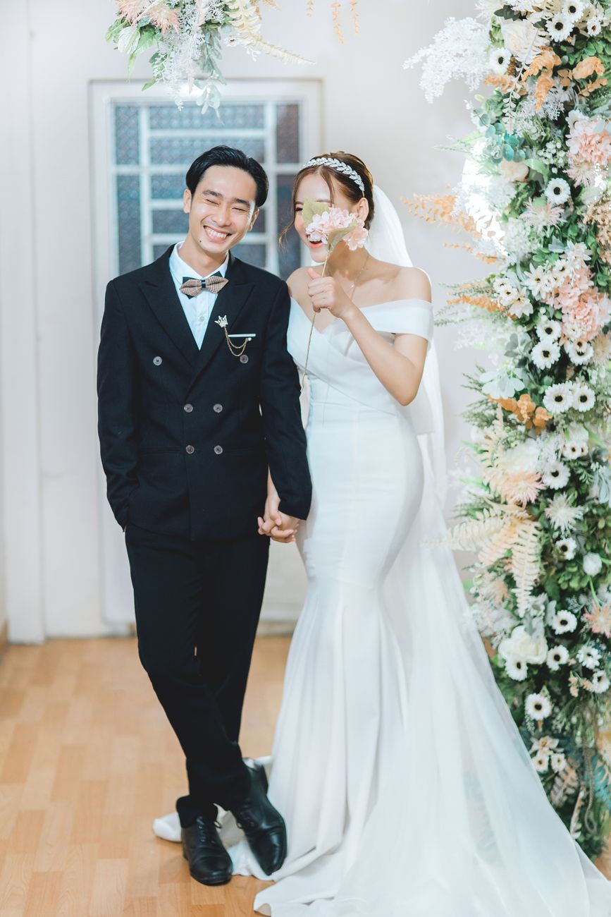 Elegant indoor wedding featuring a joyful couple holding hands with floral decor.