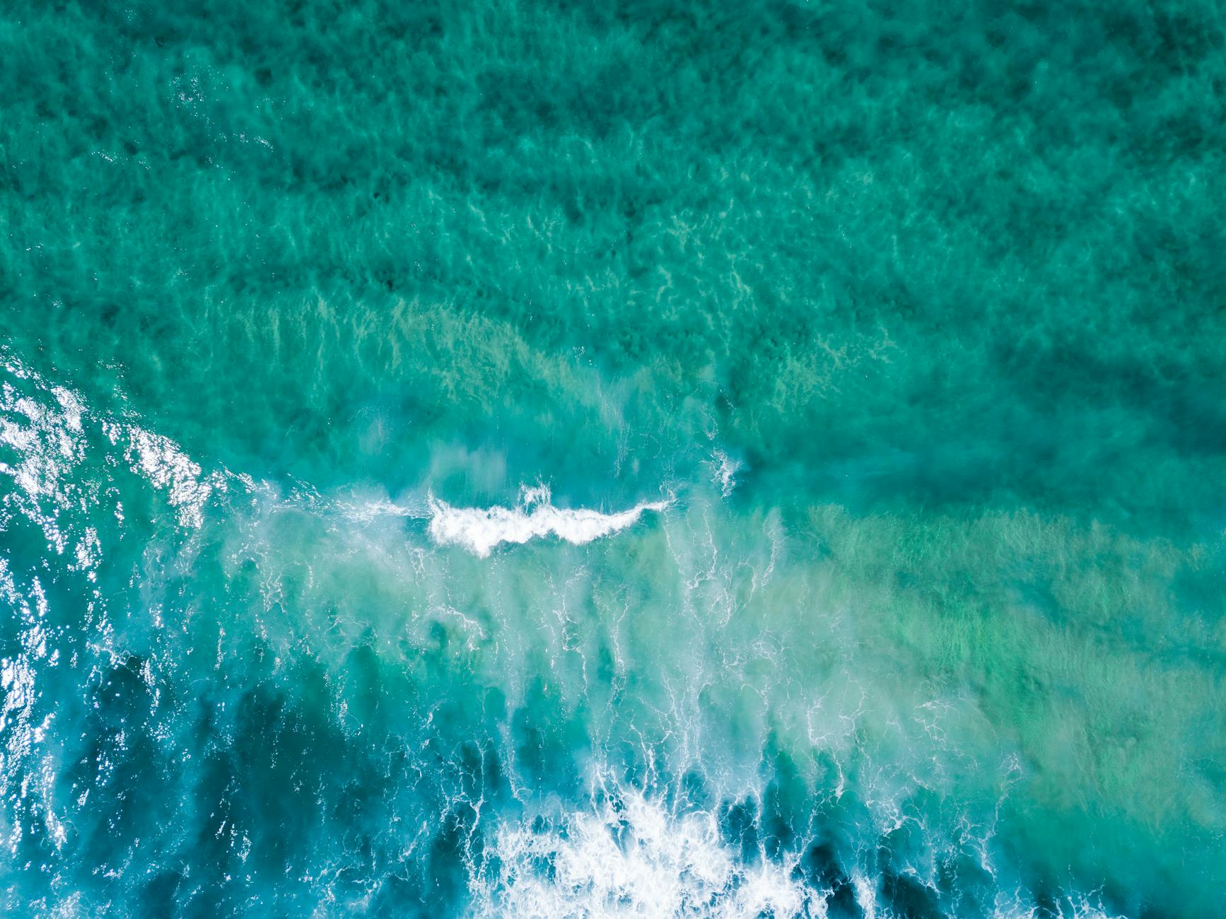 Stunning aerial view of turquoise ocean waves creating a vibrant, textured seascape.