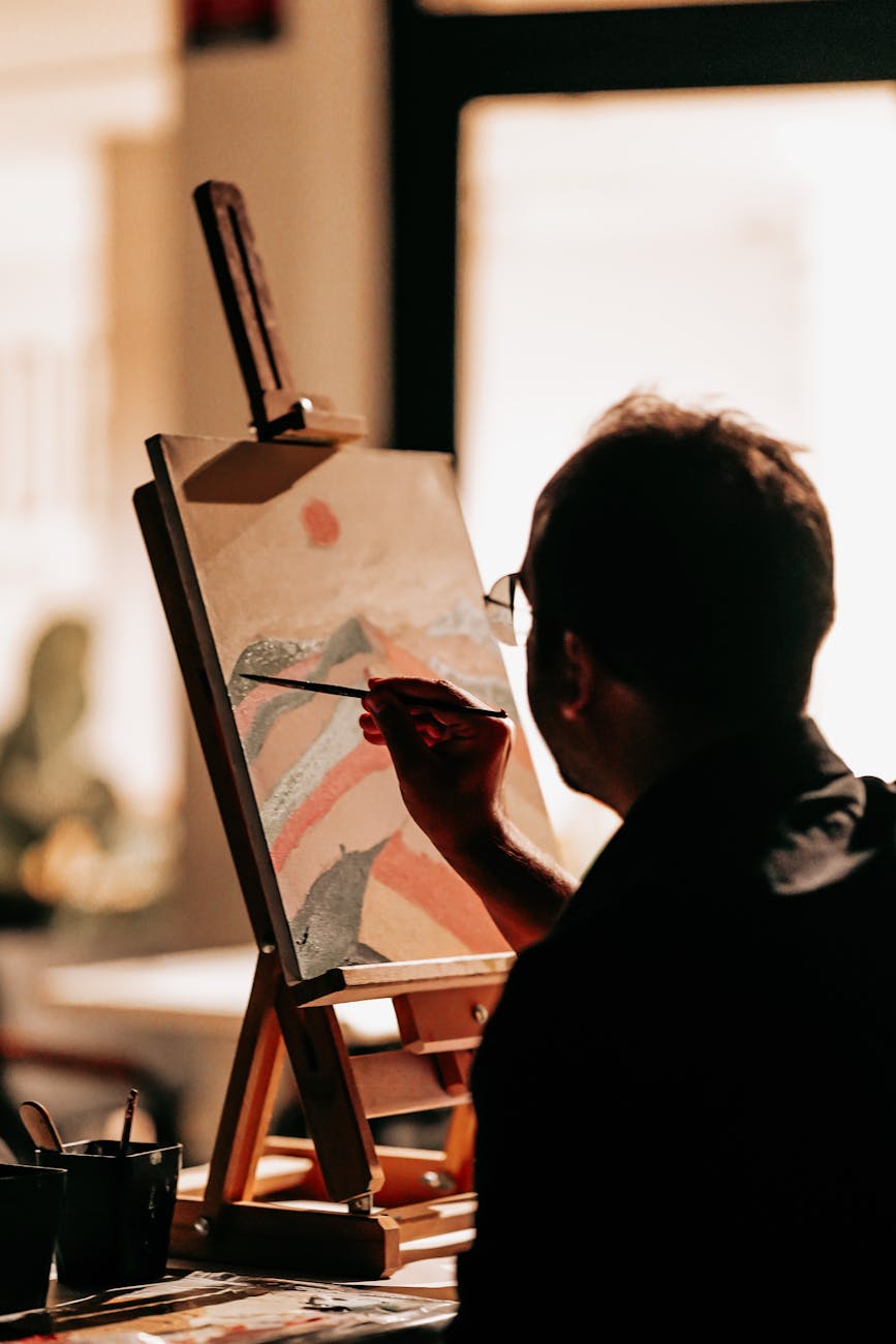 A male artist concentrating intently as he paints an abstract piece indoors in Ankara, Türkiye.
