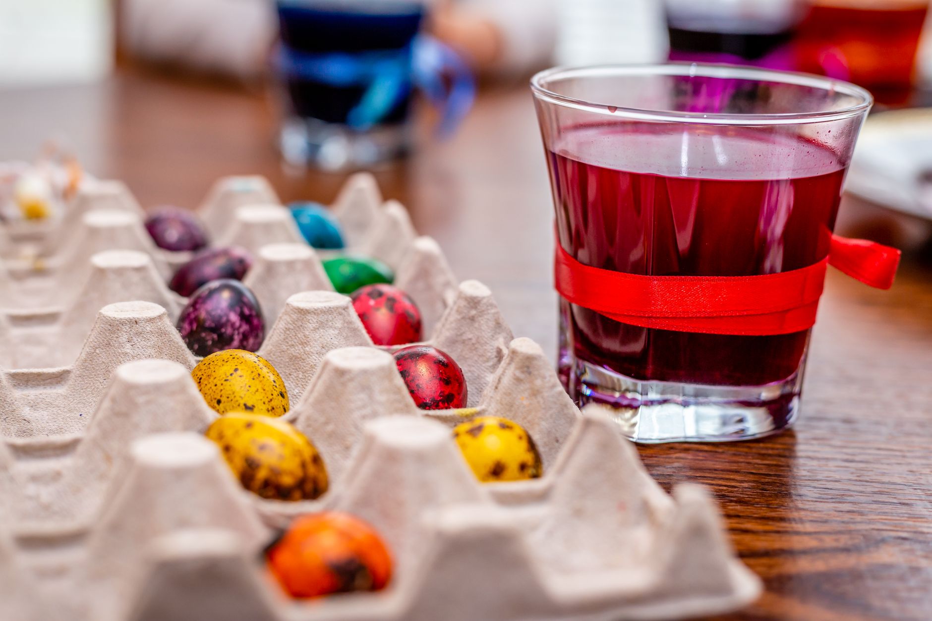 Colorful Easter eggs on a palette tray with a glass of red dye, perfect for Easter decoration concepts.