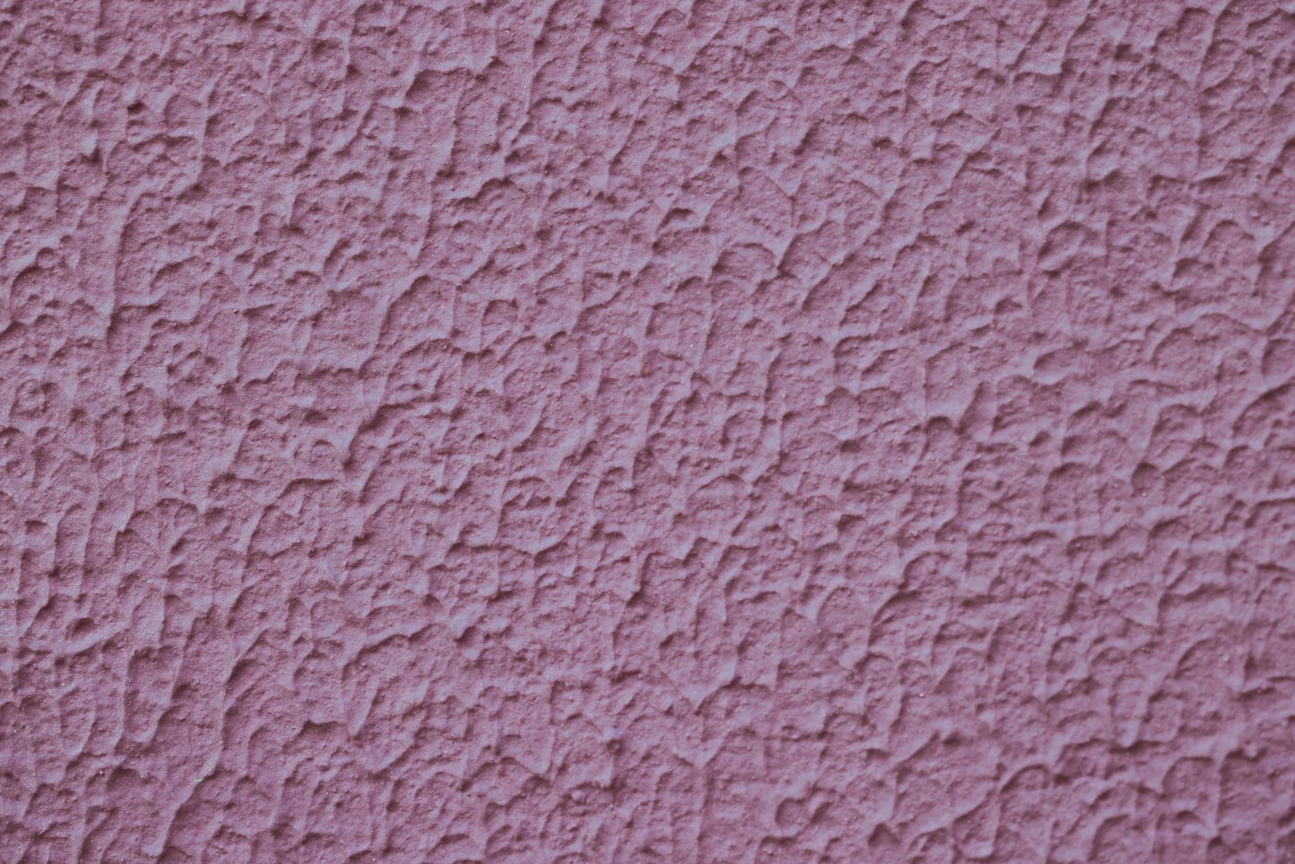 Detailed close-up of a pink textured wall surface creating a rough visual pattern.