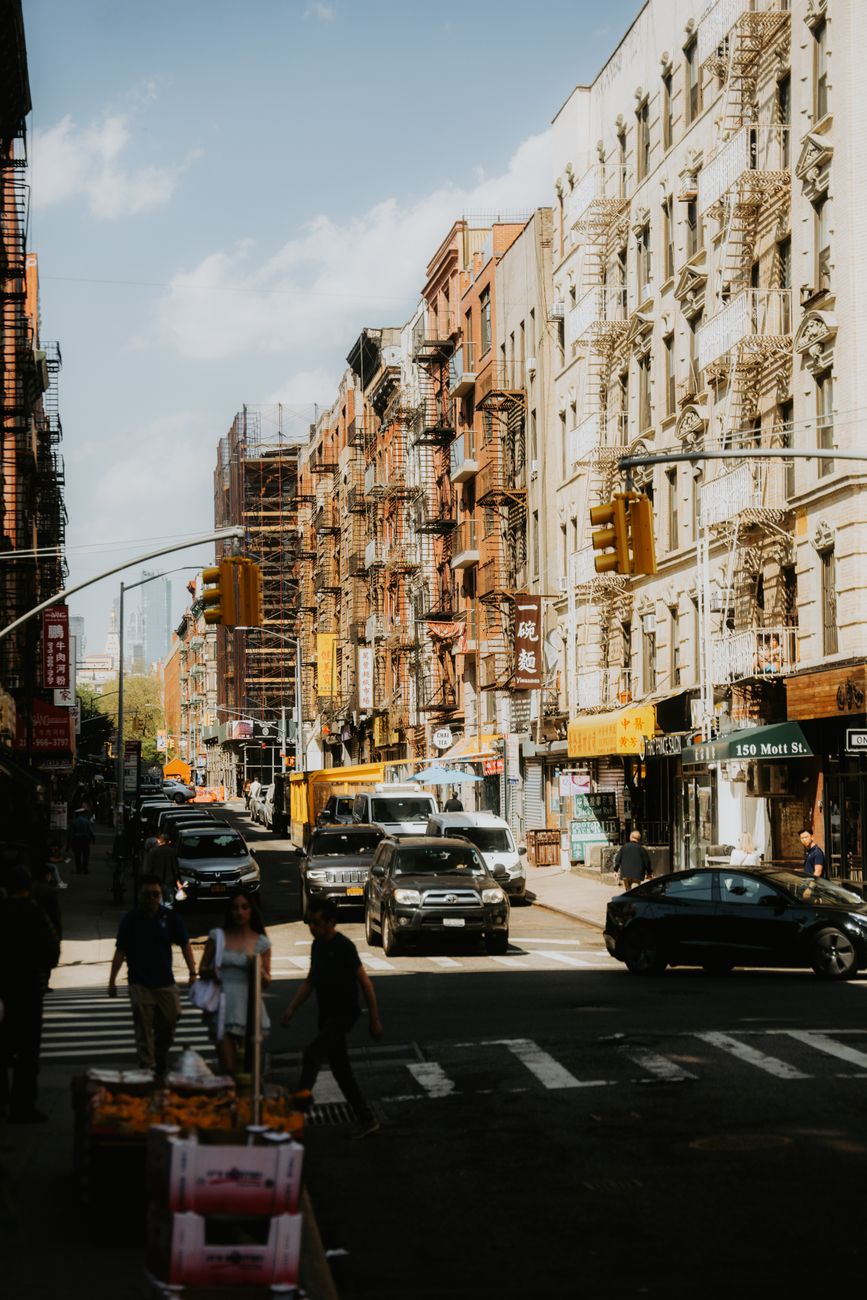 Lively city street filled with cars and pedestrians under bright daylight.