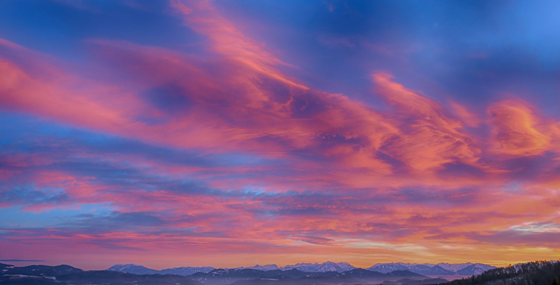 Stunning sunset with pink and orange hues over a mountainous horizon.