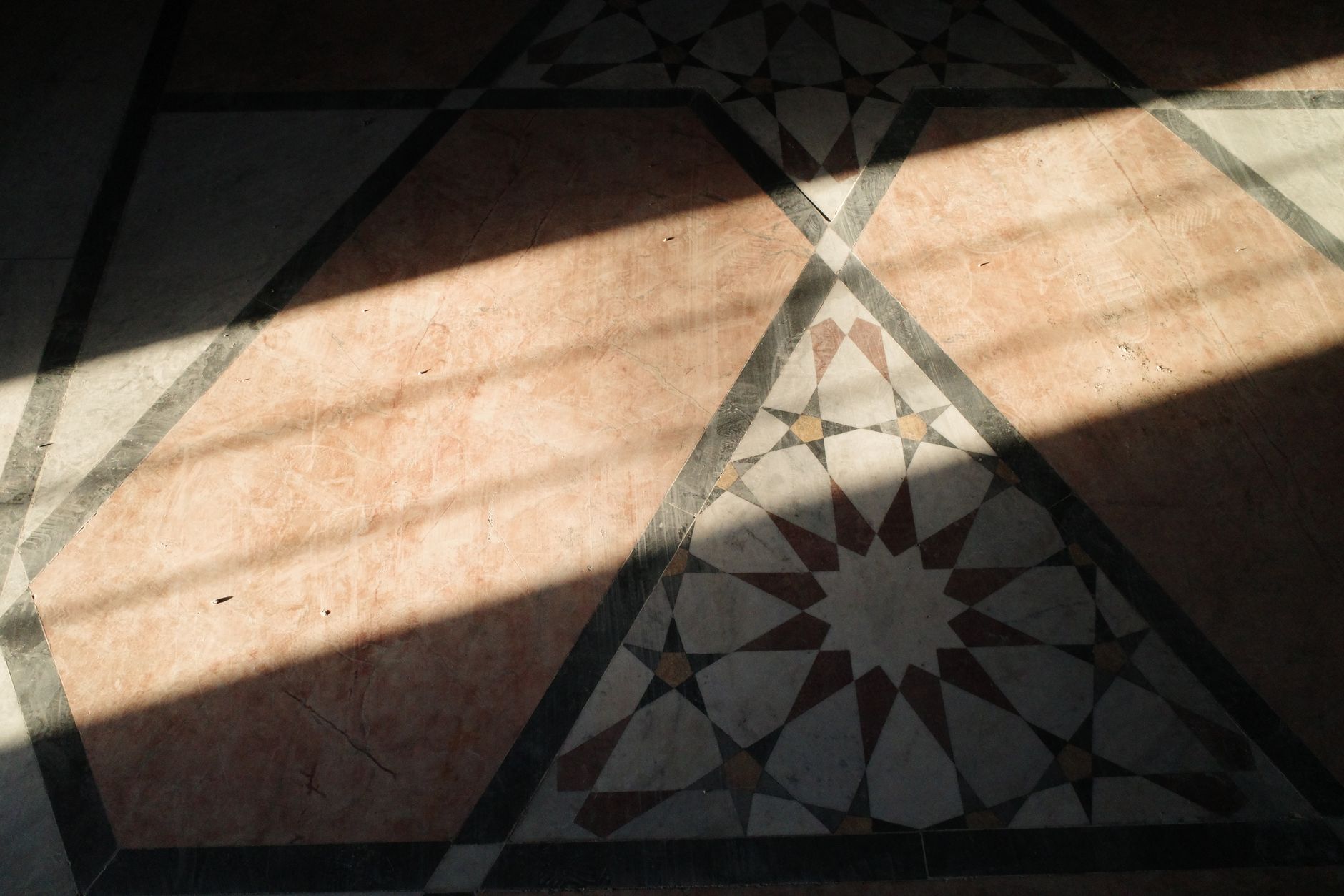 Sunlight casts shadows on a geometric tile floor in Aleppo, Syria, creating an artistic display.