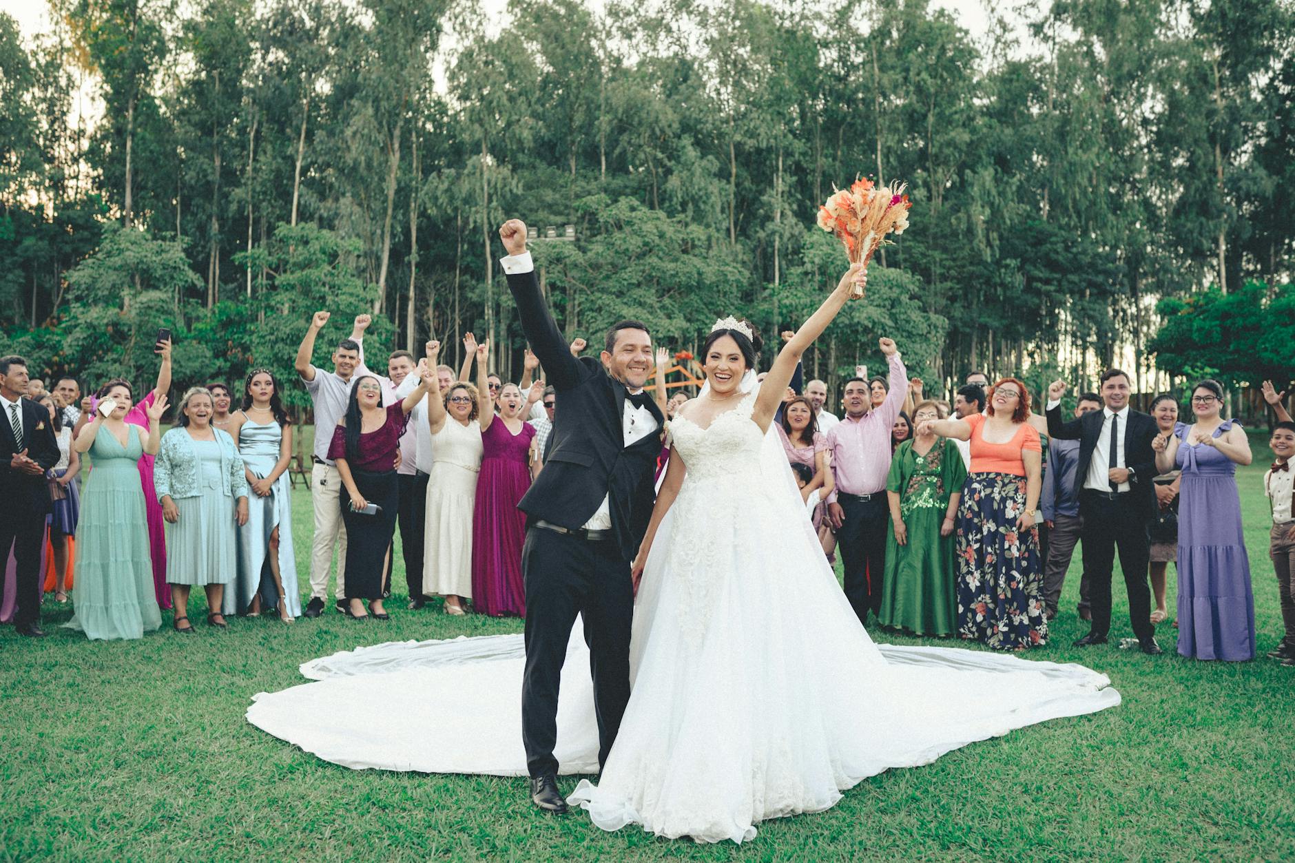 Bride and groom celebrate with guests outdoors in a vibrant summer wedding ceremony.