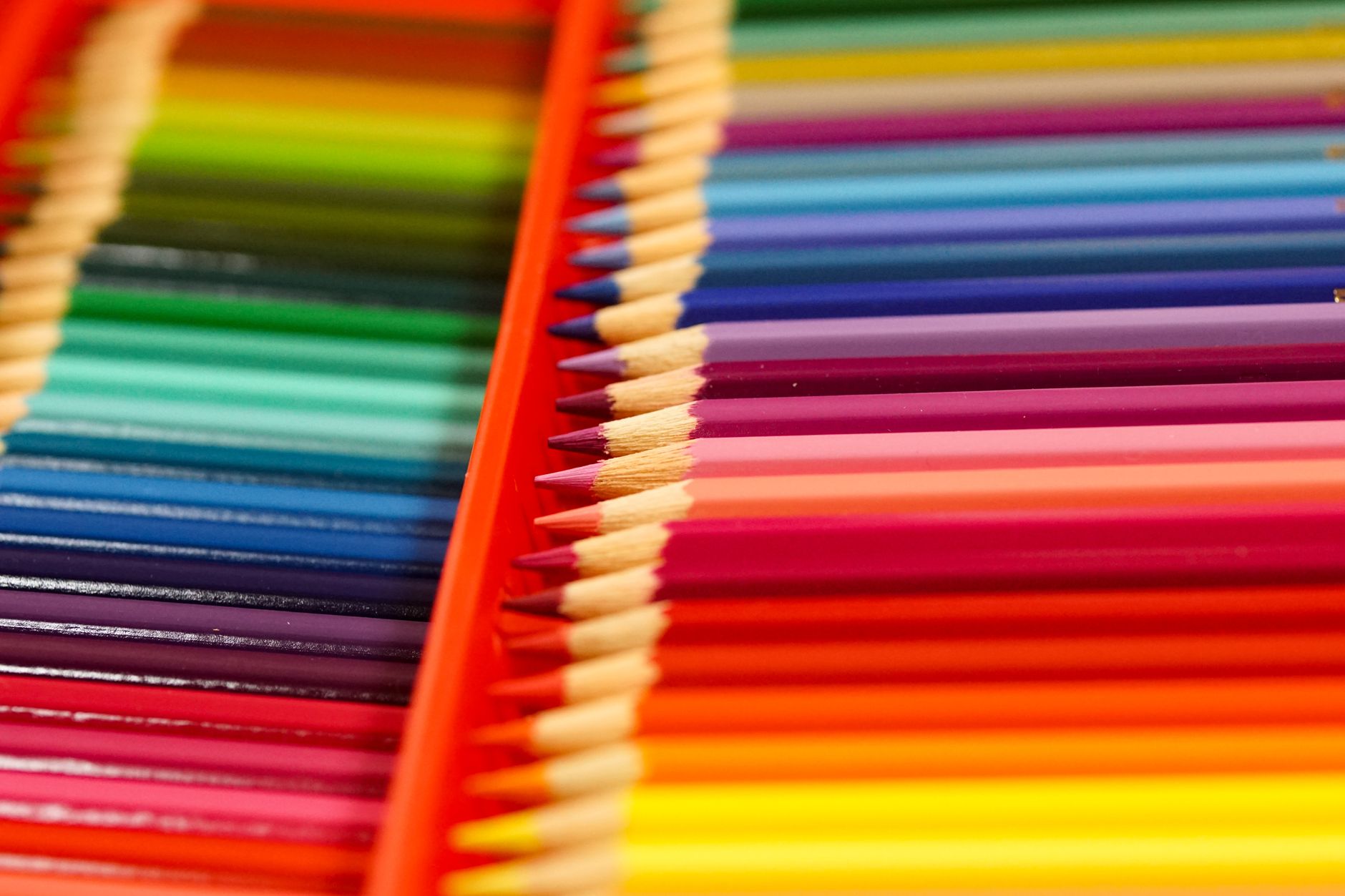 Vibrant colored pencils arranged neatly in a box, showcasing a spectrum of colors in a close-up view.