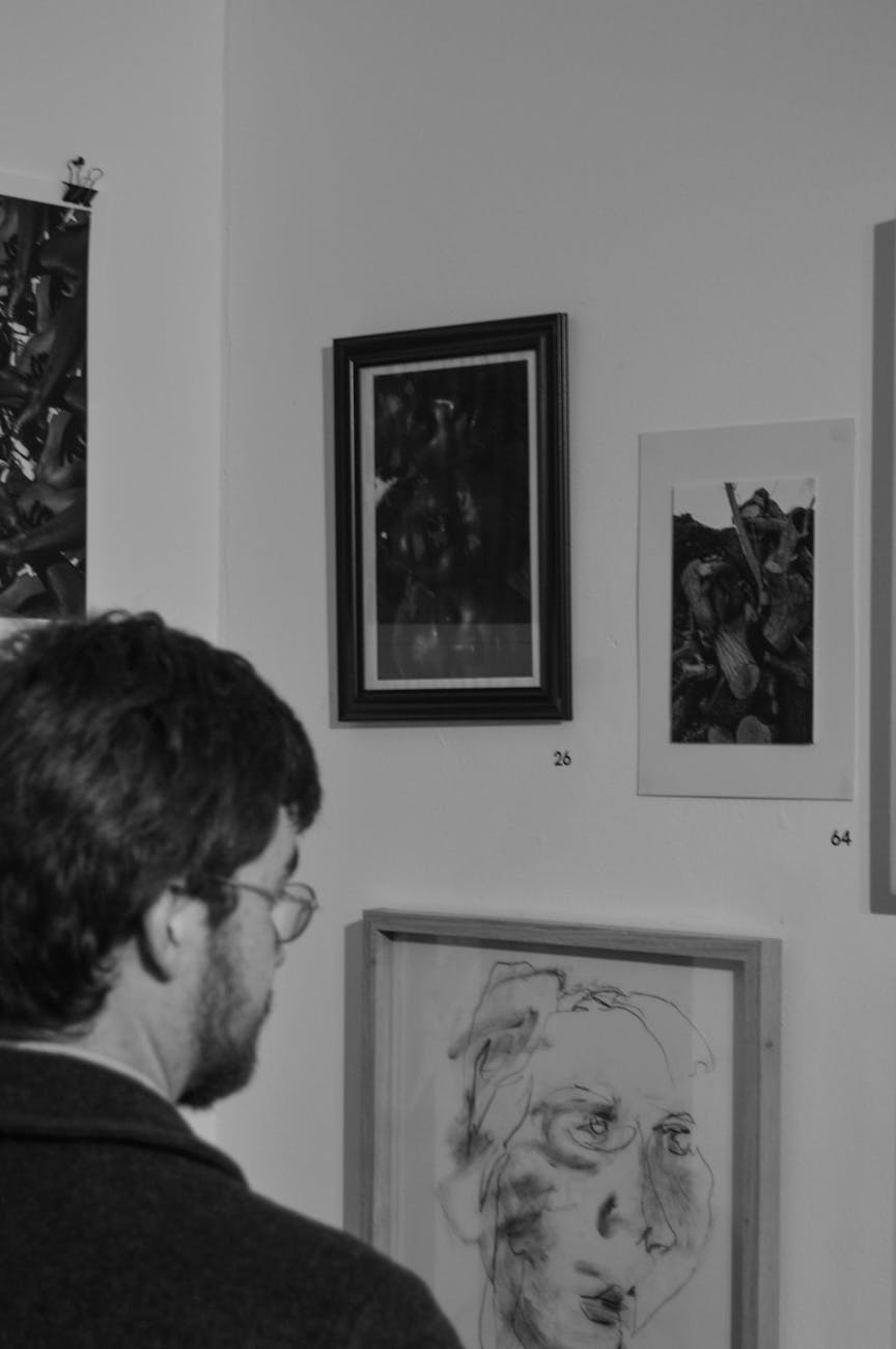 Man admiring framed artwork in a Cape Town gallery. Black and white photography enhances the art ambiance.