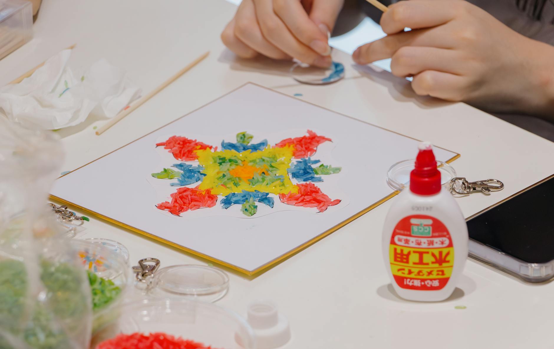 Colorful mosaic art creation using glue and beads in a classroom setting in Shinjuku, Tokyo.