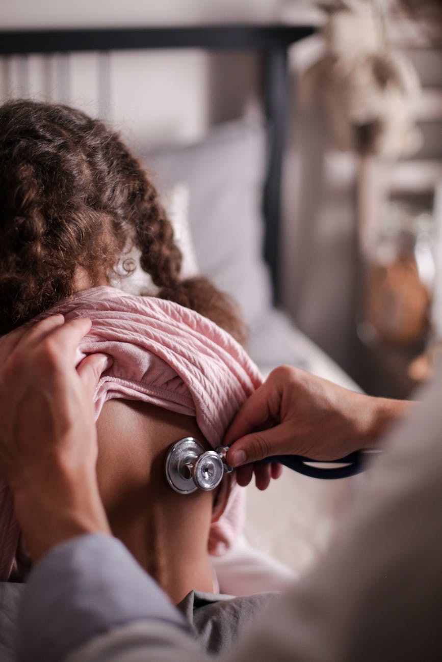 Doctor using stethoscope to check child's back during a health examination indoors.