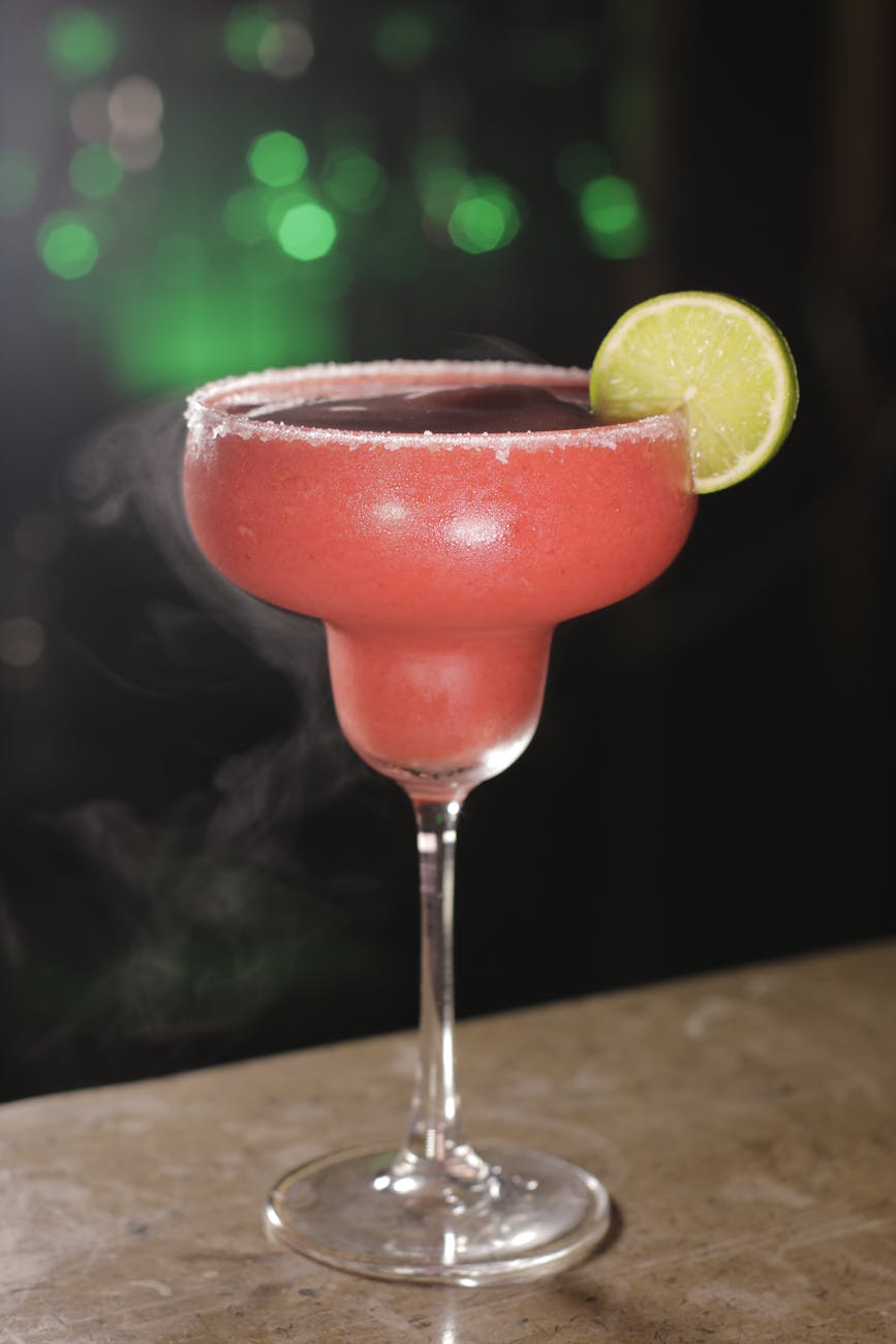 Delicious strawberry margarita garnished with lime on a bar counter, perfect for cocktails.