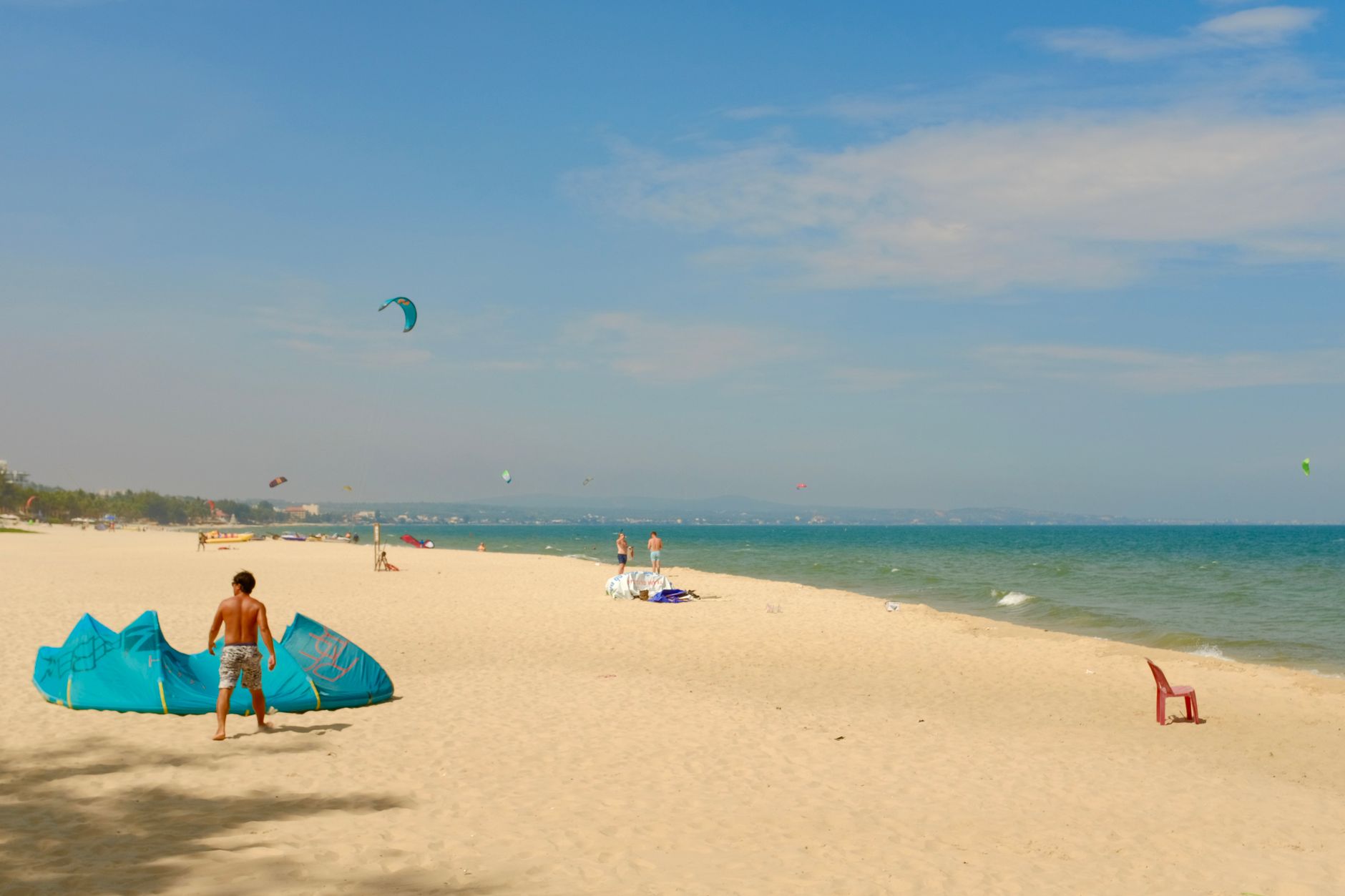 Beach activity with kite surfers on a sunny day in Binh Thuan, Vietnam.